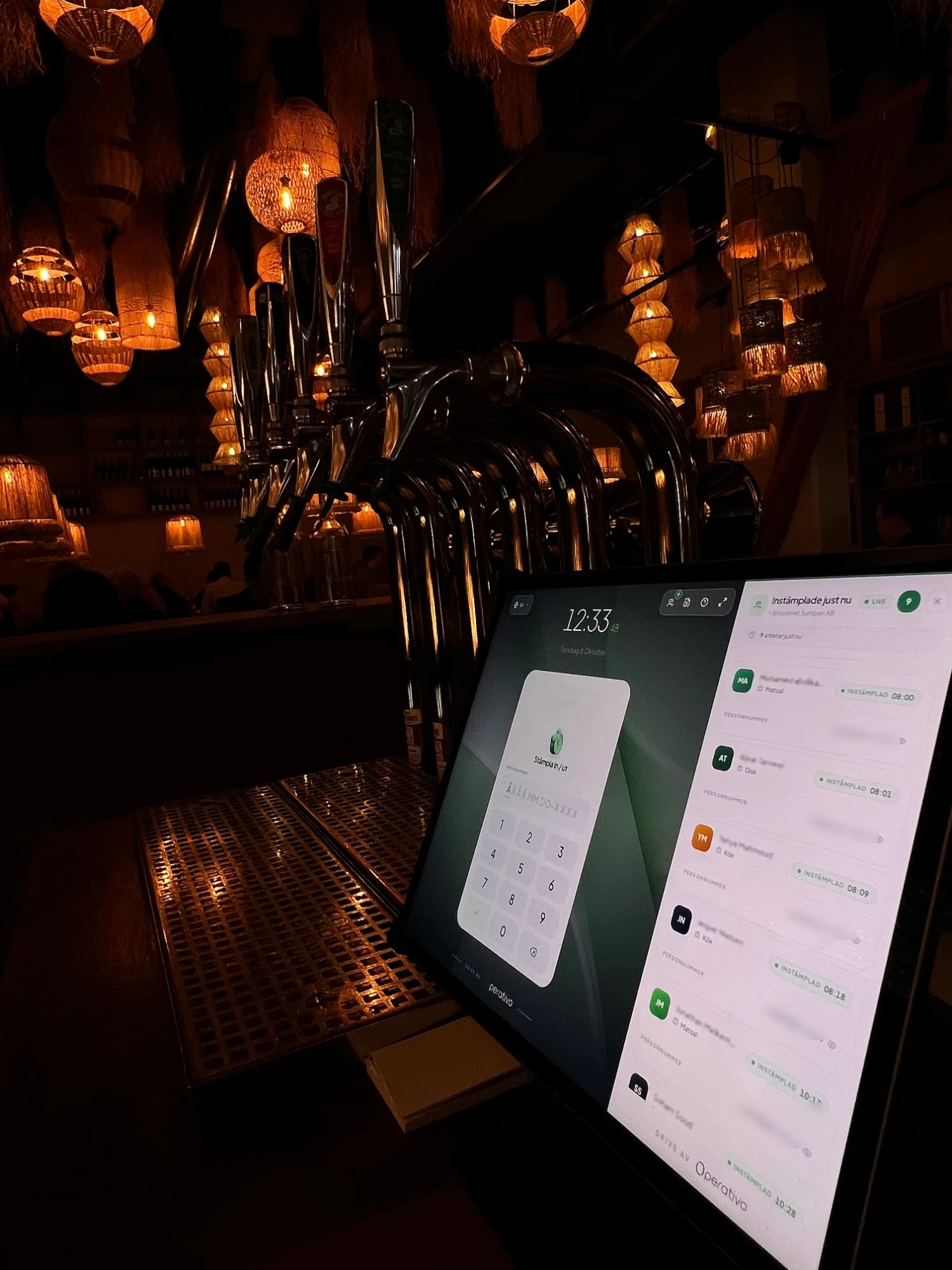 Operativos stämpelklocka på en surfplatta vid baren i en restaurang, med personal som stämplat in